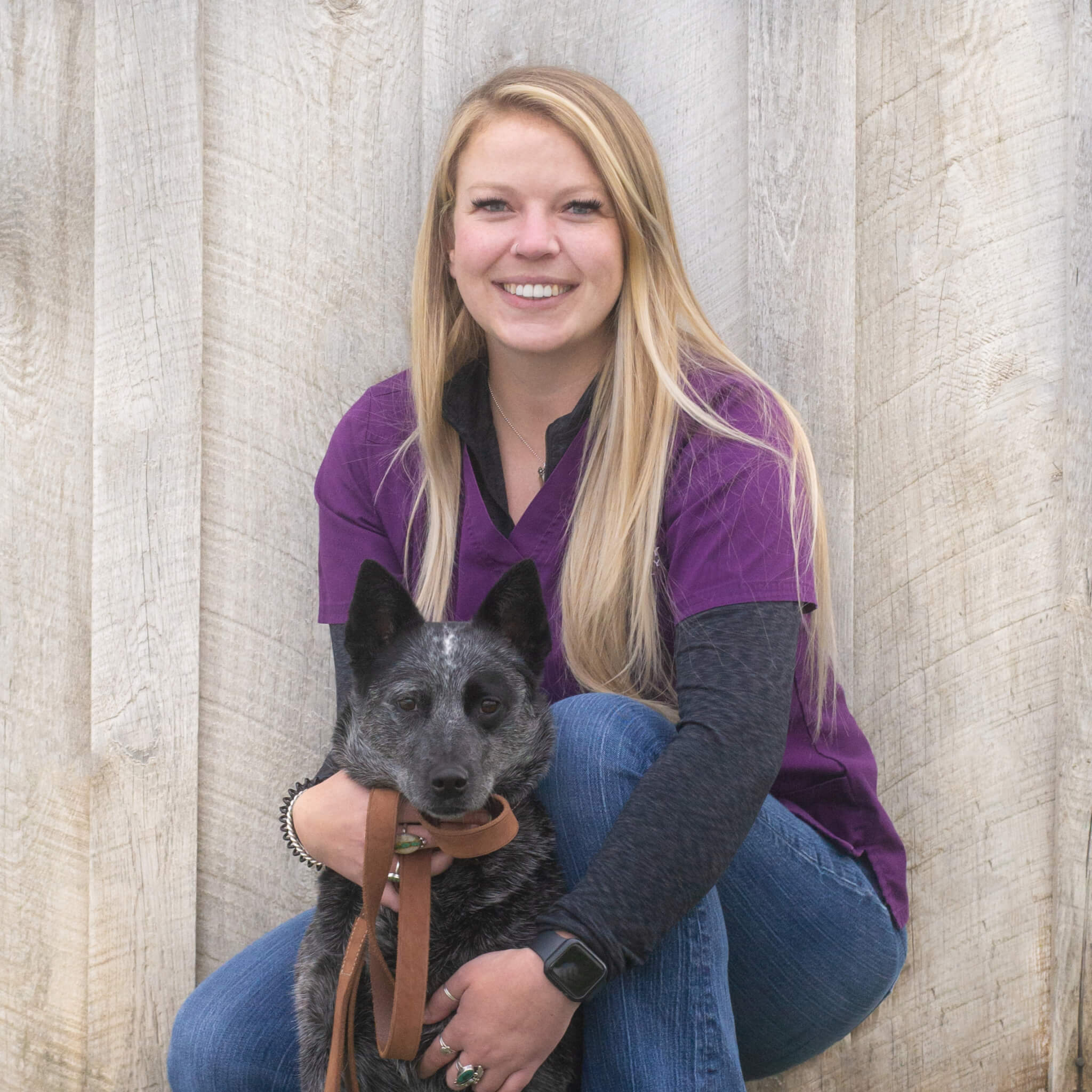 Veterinary assistant, Morgan, kneels down with a dog in Bozeman